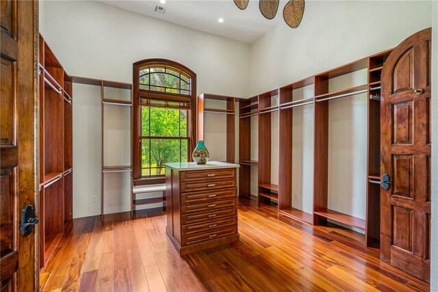 walk in closet featuring a towering ceiling and hardwood / wood-style flooring