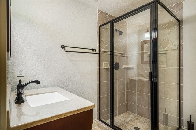 bathroom featuring vanity, a shower with shower door, and a textured ceiling