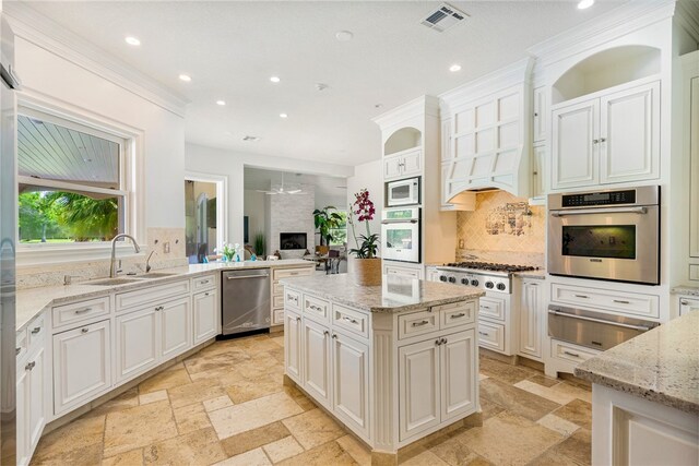 kitchen featuring appliances with stainless steel finishes, sink, light stone counters, and backsplash