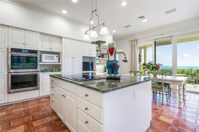 596 Ocean Rd, Vero Beach, FL 32963 - kitchen with double oven, ornamental molding, white microwave, a kitchen island, and black electric stovetop
