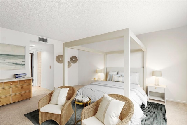 bedroom featuring visible vents, light carpet, and a textured ceiling