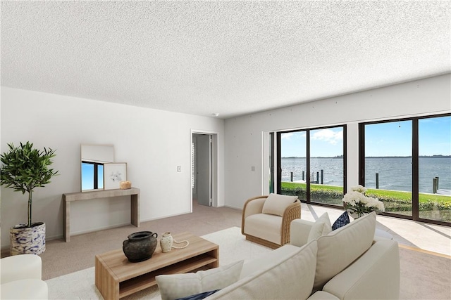 living room with a water view, light carpet, baseboards, and a textured ceiling