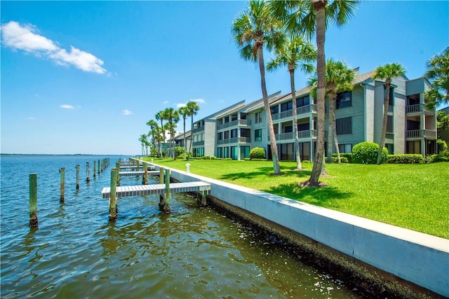 view of dock with a water view and a yard