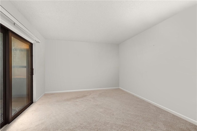 empty room featuring baseboards, a textured ceiling, and light colored carpet