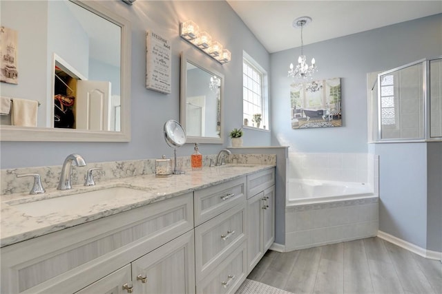 bathroom with vanity, shower with separate bathtub, hardwood / wood-style floors, and an inviting chandelier