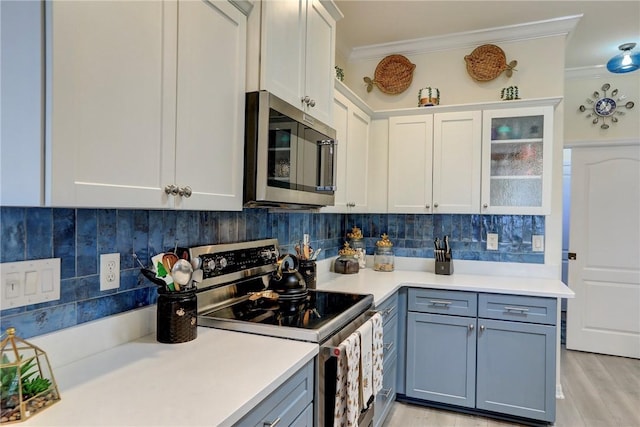 kitchen with white cabinetry, backsplash, ornamental molding, and appliances with stainless steel finishes