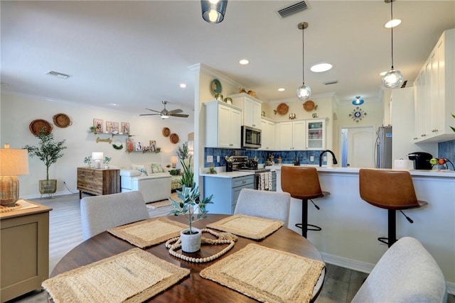 dining space featuring crown molding, sink, ceiling fan, and light hardwood / wood-style flooring