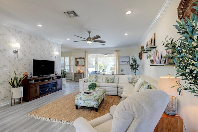 living room featuring ceiling fan, ornamental molding, and light wood-type flooring