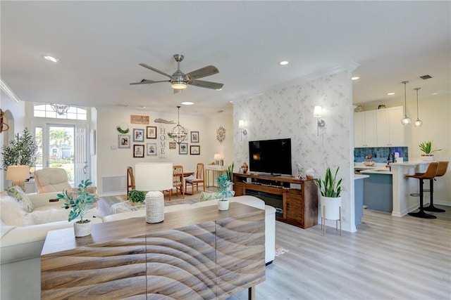 living room with ceiling fan, crown molding, and light hardwood / wood-style floors