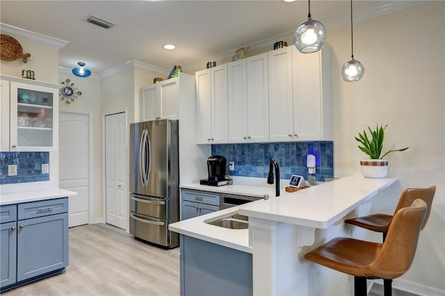 kitchen with a breakfast bar, decorative light fixtures, stainless steel fridge, kitchen peninsula, and white cabinets