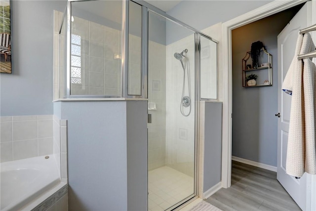 bathroom featuring wood-type flooring and shower with separate bathtub