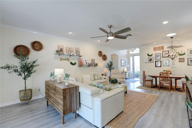 living room featuring ceiling fan with notable chandelier, wood-type flooring, and ornamental molding