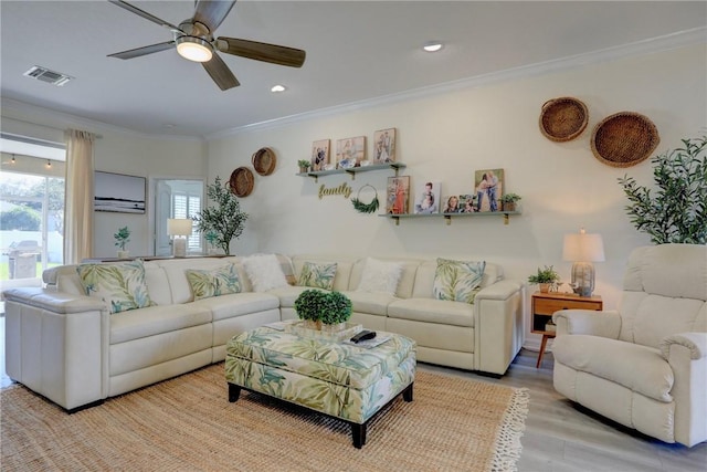 living room with crown molding, ceiling fan, a wall unit AC, and light wood-type flooring