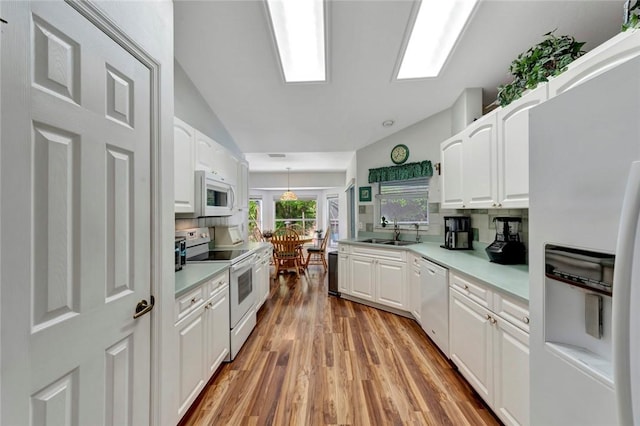 8145 95th Ct, Vero Beach, FL 32967 - kitchen with a sink, light wood-style floors, white cabinetry, vaulted ceiling, and white appliances