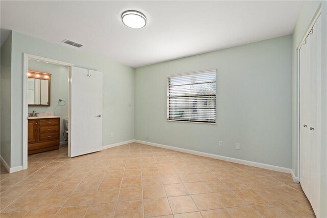 2906 1st St, Vero Beach, FL 32968 - unfurnished bedroom with light tile patterned floors, ensuite bathroom, a closet, visible vents, and baseboards