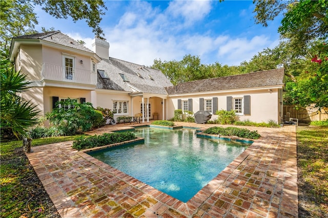 back of property featuring a balcony, a fenced in pool, a patio, and french doors