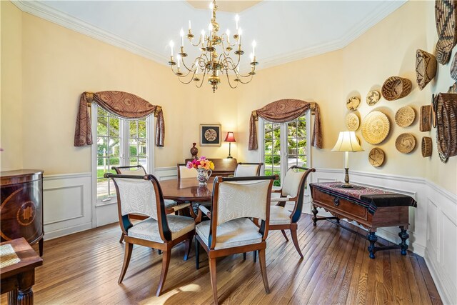 dining space with wood-type flooring, a healthy amount of sunlight, and crown molding