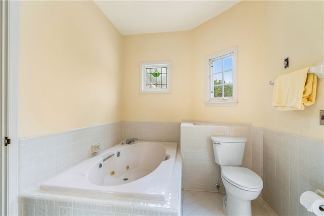 bathroom with tile walls, tile patterned flooring, tiled tub, and toilet