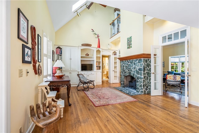 living room with a fireplace, track lighting, high vaulted ceiling, hardwood / wood-style flooring, and ceiling fan