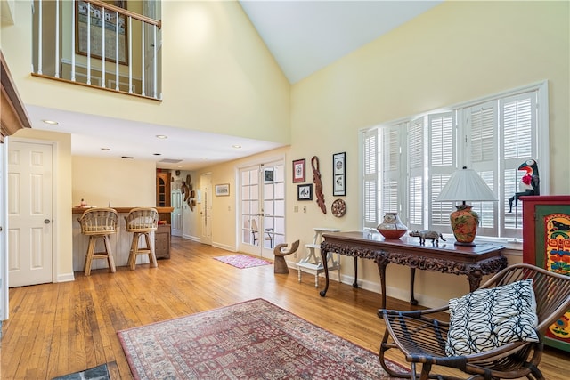 sitting room with high vaulted ceiling, french doors, and light hardwood / wood-style flooring