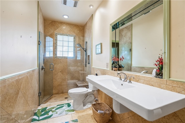 bathroom with tile patterned floors, toilet, tile walls, sink, and walk in shower