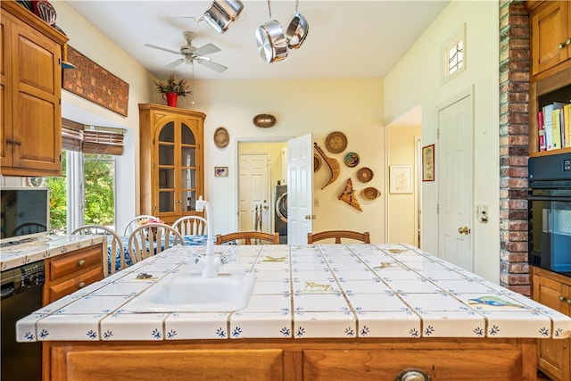 kitchen featuring tile counters, black appliances, ceiling fan, and a center island