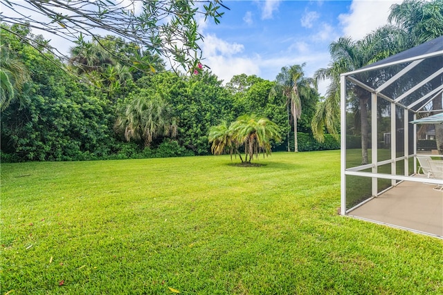 view of yard with glass enclosure and a patio