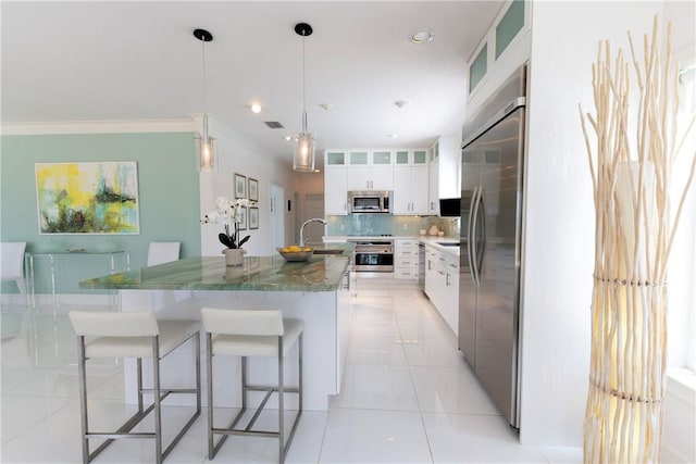 116 Ocean Way, Vero Beach, FL 32963 - kitchen with appliances with stainless steel finishes, an island with sink, ornamental molding, tasteful backsplash, and a breakfast bar area