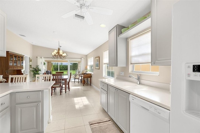 4951 Corsica Sq, Vero Beach, FL 32967 - kitchen with white appliances, light tile patterned floors, light countertops, a chandelier, and vaulted ceiling