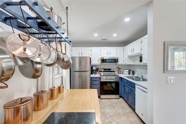 kitchen featuring white cabinetry, stainless steel appliances, blue cabinets, sink, and a textured ceiling