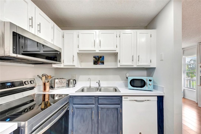 kitchen with hardwood / wood-style floors, sink, white cabinetry, a textured ceiling, and stainless steel appliances