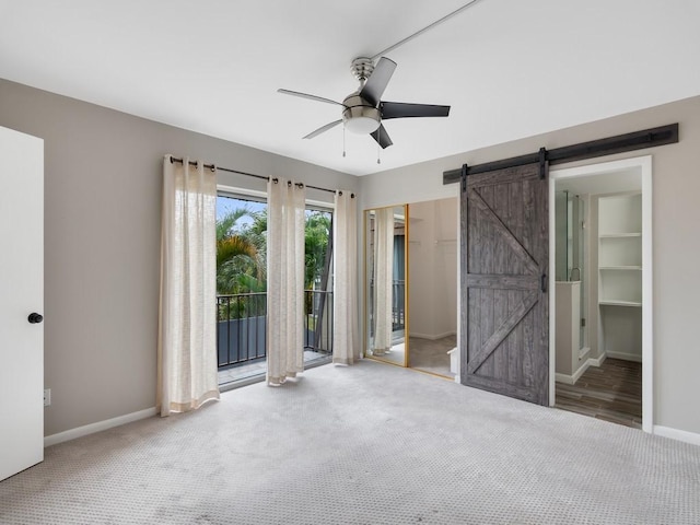 unfurnished bedroom with a barn door, carpet flooring, access to outside, and a closet