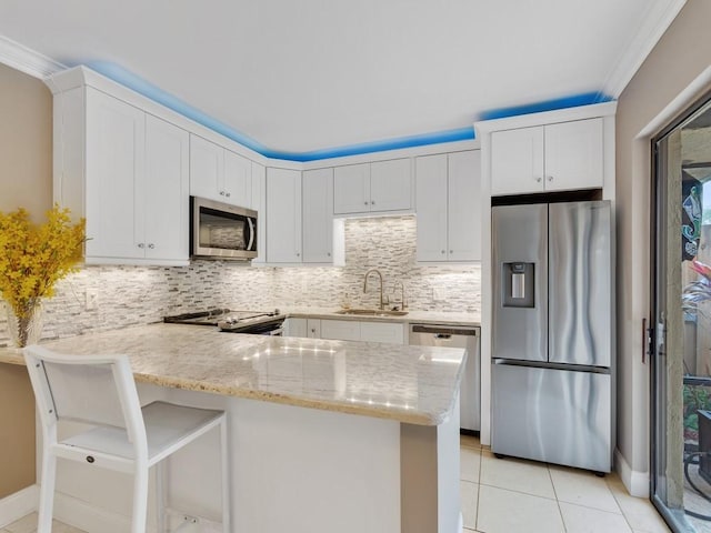 kitchen with sink, a breakfast bar, appliances with stainless steel finishes, white cabinets, and kitchen peninsula