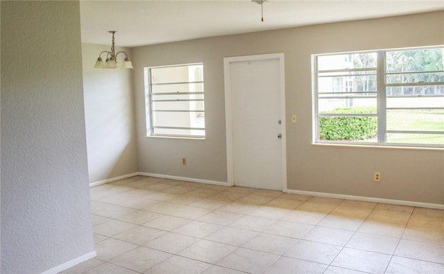 unfurnished room featuring a notable chandelier, baseboards, and light tile patterned floors