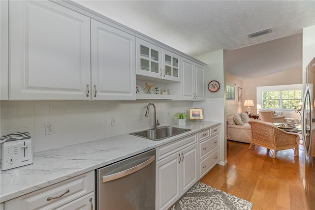 kitchen featuring light stone counters, vaulted ceiling, sink, stainless steel dishwasher, and light hardwood / wood-style flooring