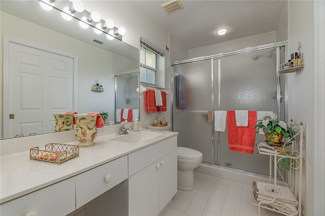 bathroom with toilet, vanity, tile patterned floors, and a shower with door