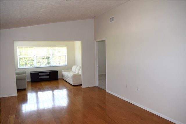 interior space featuring hardwood / wood-style flooring, a textured ceiling, and vaulted ceiling