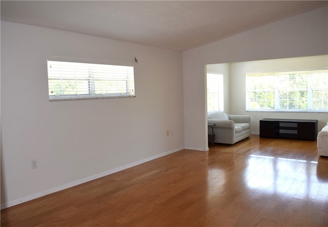 empty room with light wood-type flooring and lofted ceiling