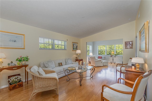 living room featuring lofted ceiling and light hardwood / wood-style flooring