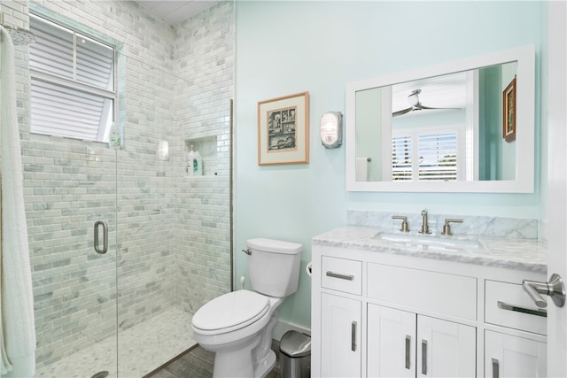 bathroom with a shower with shower door, vanity, and toilet