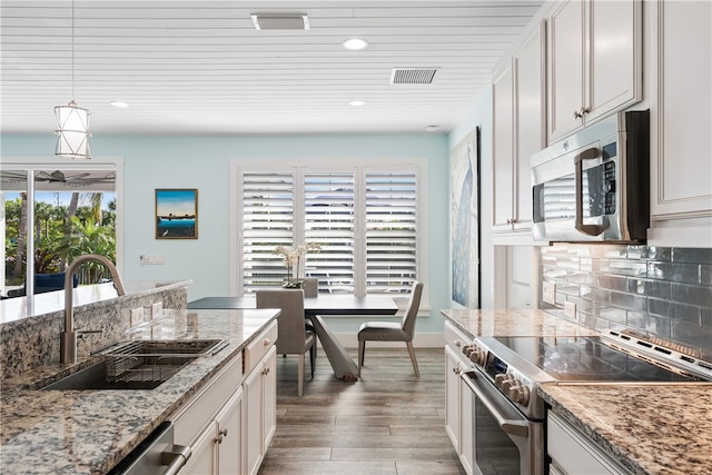 kitchen featuring white cabinets, appliances with stainless steel finishes, and plenty of natural light