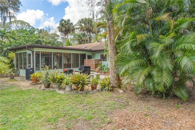 rear view of property with a lawn, a patio area, and a sunroom