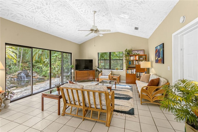 living area with lofted ceiling, a healthy amount of sunlight, ceiling fan, and light tile patterned floors