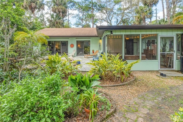 rear view of property featuring a sunroom and a patio