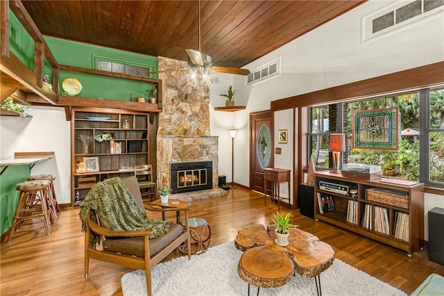 living area featuring wooden ceiling, a fireplace, wood finished floors, visible vents, and baseboards