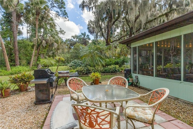 view of patio featuring a sunroom, outdoor dining area, and area for grilling