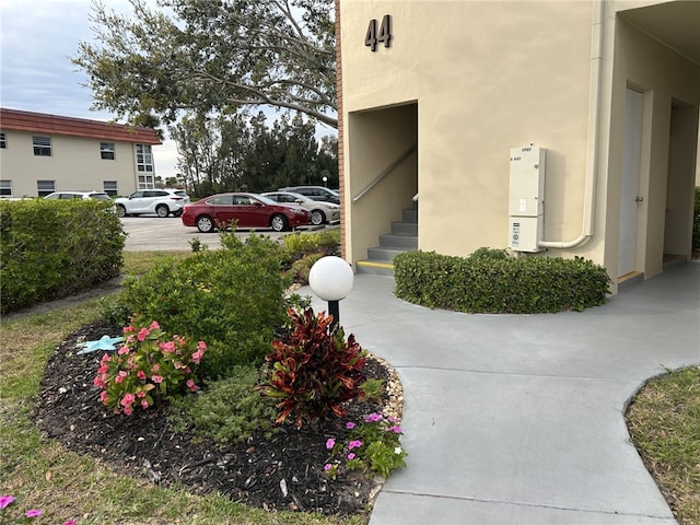 exterior space featuring stairs, uncovered parking, and stucco siding