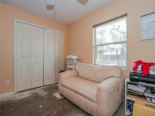 sitting room with unfinished concrete flooring and ceiling fan