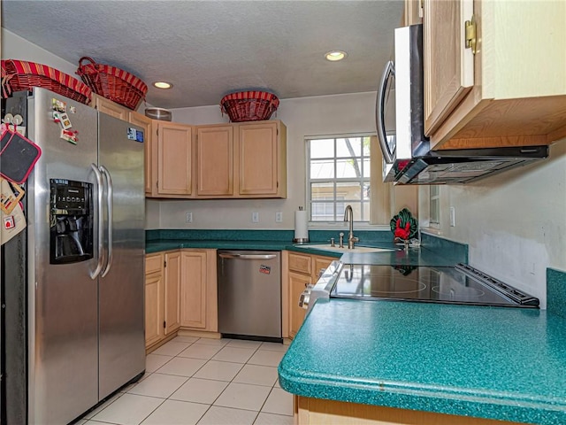 kitchen with light tile patterned floors, a sink, light brown cabinetry, stainless steel appliances, and a textured ceiling