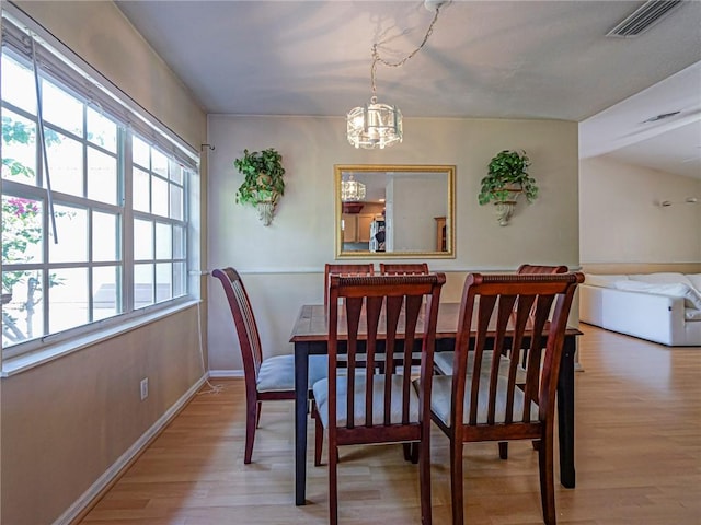 dining space featuring a notable chandelier, visible vents, baseboards, and wood finished floors